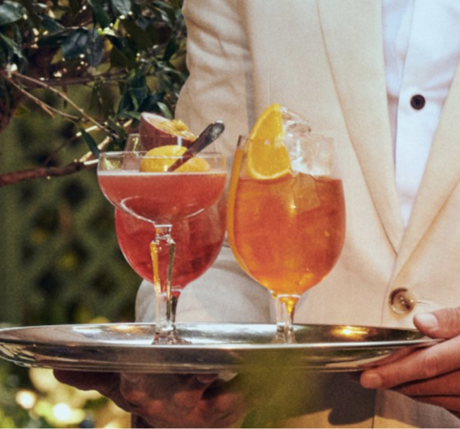 Ivy Cafe waiter carrying 2 cocktails on tray